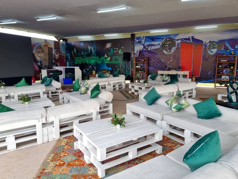 Cover of the Safaricom Emerald album: a Life Elevated VIP lounge with white pallet seating, green cushions and vintage-car murals
