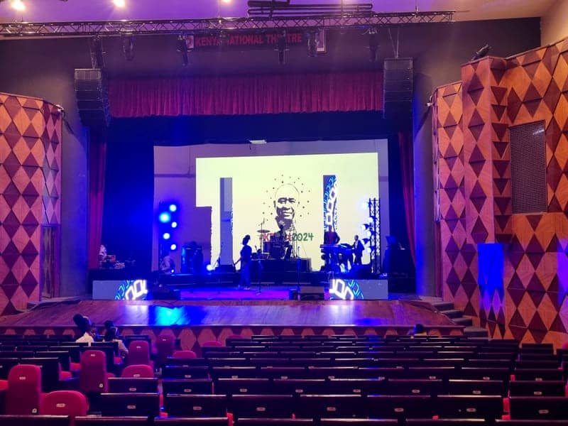 Cover of the Kenya National Theatre album: a lit theatre stage with a band setup and an LED screen at Kenya National Theatre